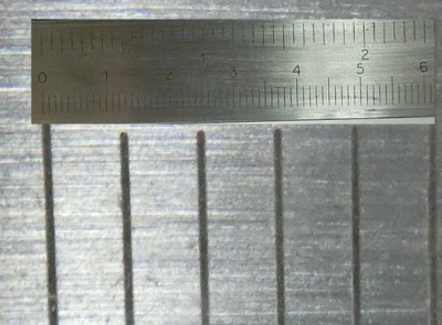 Fotomontáž dvou snímků - šuplera z 25 cm a zblízka přes lupu při stejně zaostřeném foťáku.